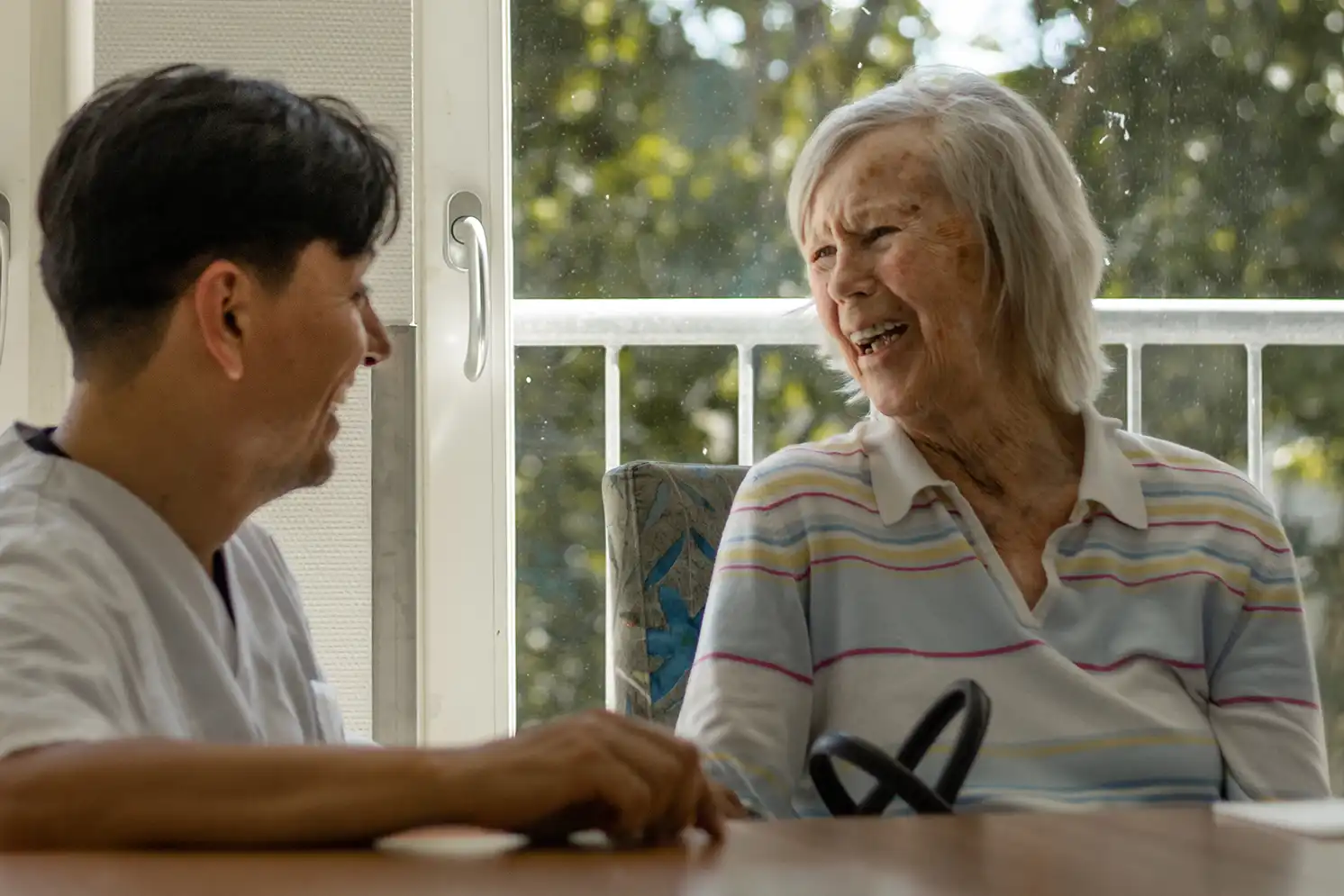 Pflegekracht und Bewohnerin lachen